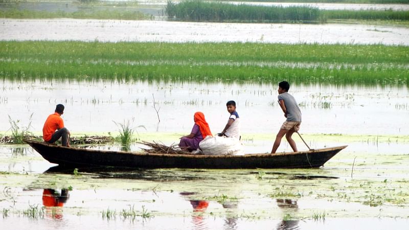 বগুড়ার শেরপুরে বাঙ্গালী নদীর পানি বৃদ্ধি পেয়ে তলিয়ে গেছে গ্রামীণ কাঁচা সড়ক। বাজার থেকে সংসারের নিত্যপণ্য কিনে নৌকার করে বাড়িতে ফিরছেন মানুষ। উপজেলার শালফা এলাকায়। ছবি: প্রথম আলো