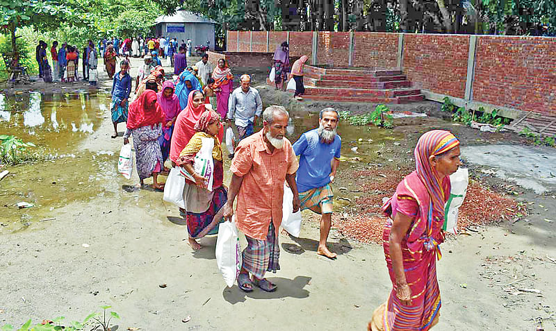 টাঙ্গাইলে বন্যার্তদের মধ্যে প্রথম আলো ট্রাস্টের পক্ষ থেকে ত্রাণসামগ্রী বিতরণ করা হয়। ত্রাণ নিয়ে বাড়ি ফিরছেন বন্যার্তরা। গতকাল ভূঞাপুরের অর্জুনা হাজি ইসমাইল খাঁ বেসরকারি কারিগরি কলেজ প্রাঙ্গণে।  ছবি: প্রথম আলো