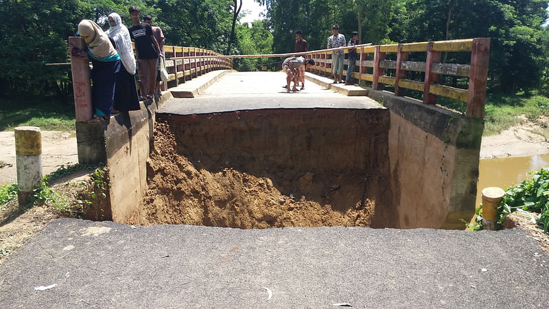 চট্টগ্রামের সাতকানিয়ায় সেতুর সংযোগ সড়ক ধসে খালে বিলীন হয়ে গেছে। এতে গাড়ি চলাচল বন্ধ হয়ে গেছে। আজ শনিবার সকালে উপজেলার মির্জাখীলের হাতিয়ার খাল সেতু এলাকায়। ছবি: মামুন মুহাম্মদ