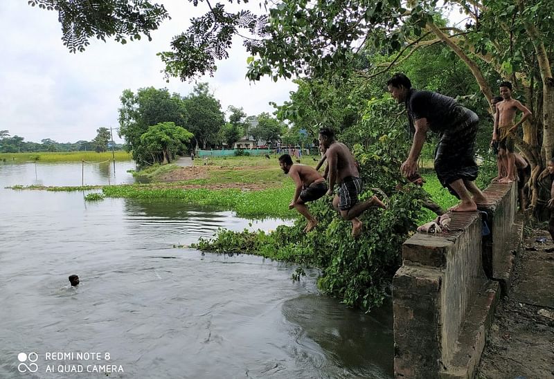 বর্ষাকাল এলেই পানিতে পূর্ণ হয়ে যায় খাল-বিল, নদী-নালা। আর শিশু-কিশোরেরাও আনন্দে মেতে ওঠে বর্ষার নতুন পানিতে। বেলা হলেই এসব জলাধারের স্বচ্ছ পানিতে ঝাঁপিয়ে পড়ে গ্রামের দুরন্ত শিশু-কিশোরেরা। বড়রাও যেন ফিরে যেতে চান সেই ফেলে আসা শৈশবের দুরন্তপনায়। উঁচু স্থান থেকে শিশুদের মতো লাফঝাঁপে কিছুক্ষণের জন্য তাঁরাও ফিরে গিয়েছিলেন মধুর শৈশবে। কাশিয়ানী, গোপালগঞ্জ, ২৯ জুলাই। ছবি: ওবাইদুল্লাহ অনিক