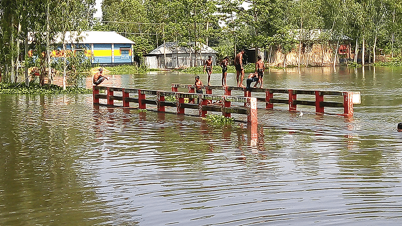 বগুড়ার শেরপুরে বন্যার পানিতে উপজেলার সুঘাট ইউনিয়নের বিনোদপুর গ্রামে যাওয়ার রাস্তাসহ সেতুটি ডুবে আছে। গতকাল তোলা ছবি। প্রথম আলো