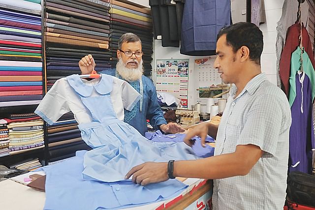 দরজির দোকানে বিভিন্ন স্কুলের পোশাক তৈরির ব্যস্ততা। মোহাম্মদপুর প্রিপারেটরি স্কুল অ্যান্ড কলেজের এক শিক্ষার্থীর জন্য তৈরি করা পোশাক দেখাচ্ছেন দোকানি আবুল বাশার। গতকাল দুপুরে রাজধানীর মোহাম্মদপুরের টাউন হল এলাকায়