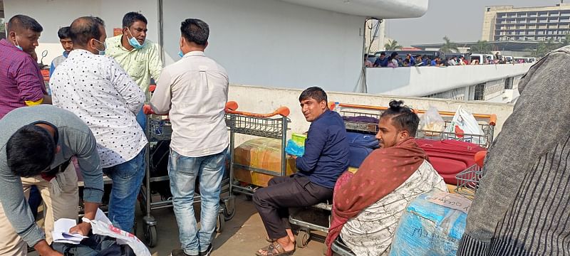 আরব আমিরাতগামী যাত্রীরা বিমানবন্দরের বহুতল কার পার্কিংয়ের ছাদে বসে খাচ্ছেন