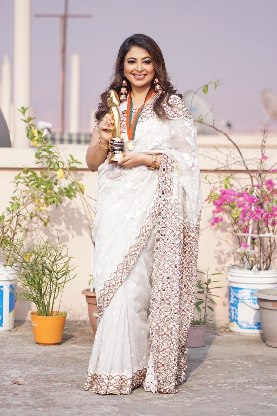 কোনালের পরনে সাদা শাড়ি, কানে লম্বা ঝুমকো, তবে সবচেয়ে আকর্ষণীয় অলঙ্কার হলো জাতীয় চলচ্চিত্র পুরস্কারের ট্রফি