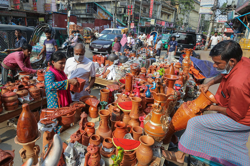  মাটির তৈরি বিভিন্ন সামগ্রী দেখছেন ক্রেতারা।