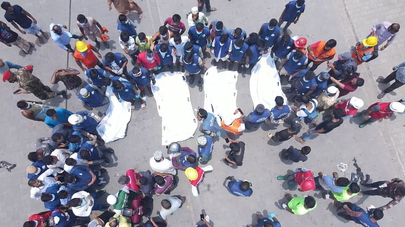 মরদেহ উদ্ধার করে এক জায়গায় নিয়ে এসে দাঁড়ান স্বেচ্ছাসেবীরা