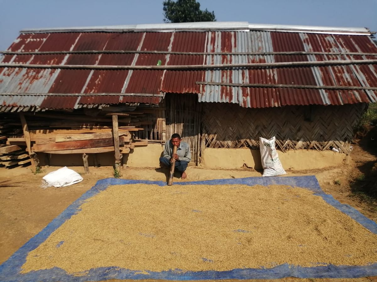 পাহাড়ের উপর গড়ে ওঠা বাড়িতে বসে ধান শুকানোর সময় চিবিদং (একধরনের হুঁকো) টানা হচ্ছে।