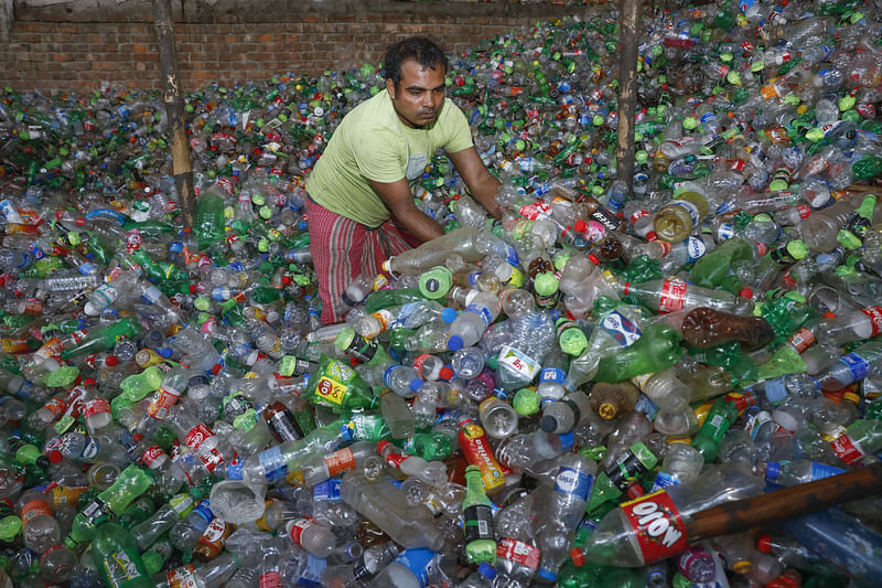 প্লাস্টিকের বোতল স্তূপ করছেন এক শ্রমিক