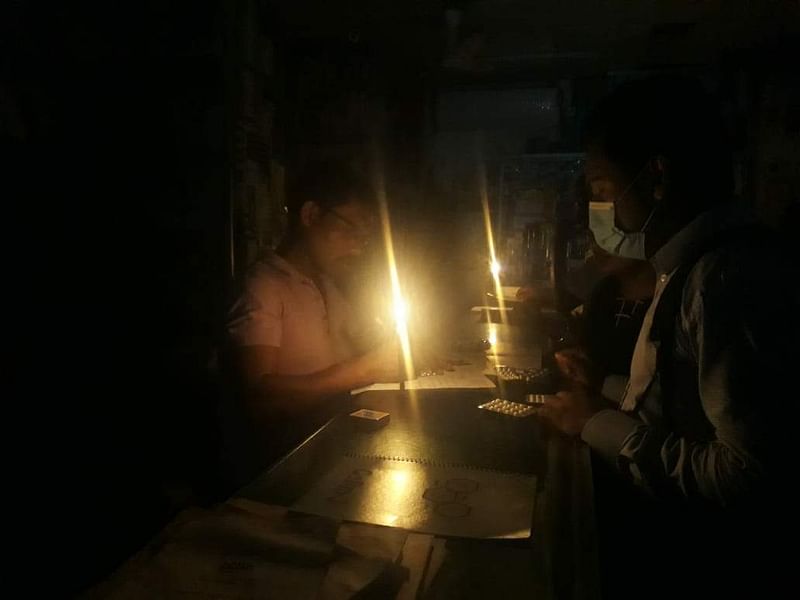 তিন ঘণ্টা বিদ্যুৎ না থাকায় মোমবাতি জ্বালিয়ে চলছে ওষুধ বিক্রি। বিকেল সাড়ে পাঁচটা, আল-রাজি ফার্মেসি, ফার্মগেট, ঢাকা