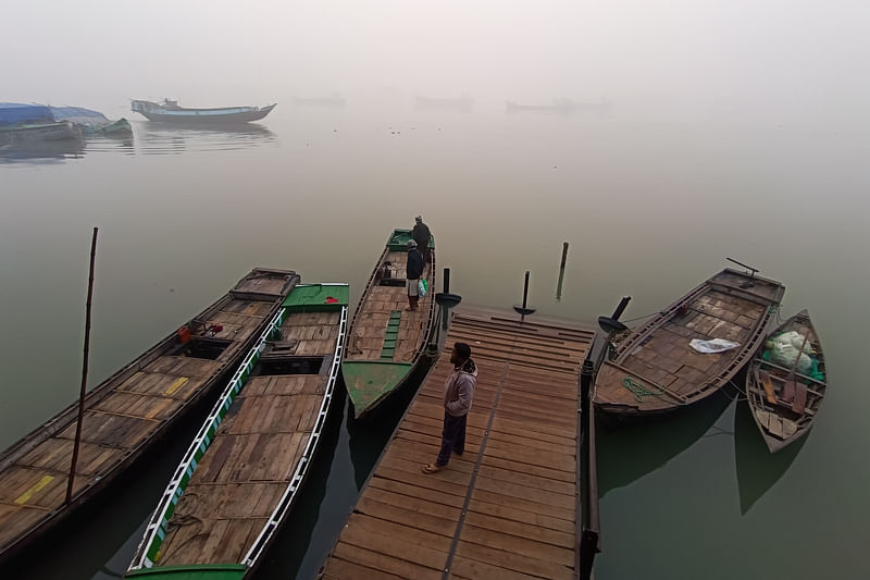 সকালে নদীর তীরে ট্রলারঘাটে যাত্রীদের জন্য অপেক্ষা করছেন এক চালক