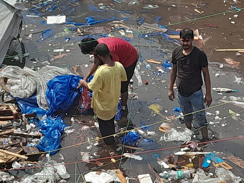 পানির ভেতর থেকে জুতাসহ অন্যান্য মালামাল খুঁজছেন ব্যবসায়ীরা