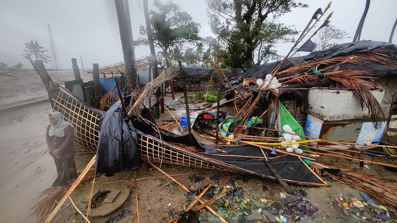 ভেঙে যাওয়া বাড়ির সামনে দাঁড়িয়ে আছেন এক নারী।