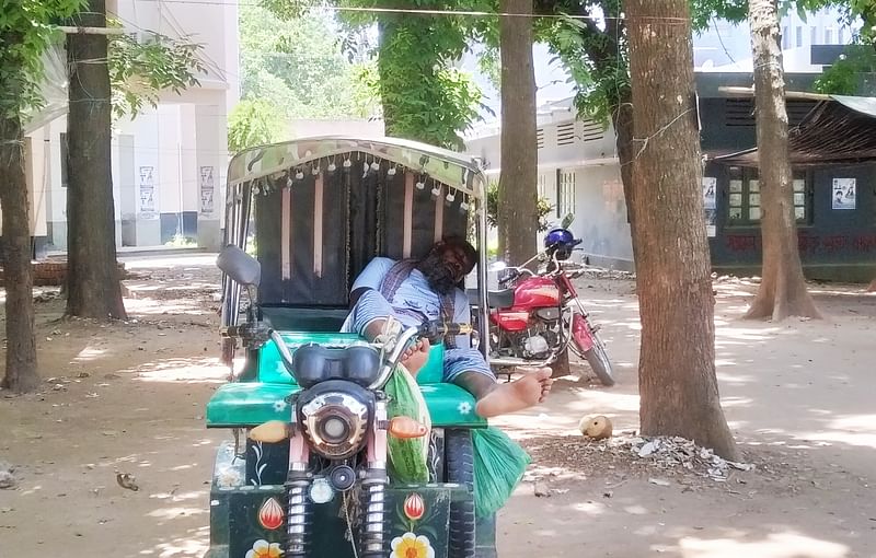 রাজশাহীতে গরমে অতিষ্ঠ হয়ে রিকশায় ঘুমাচ্ছেন এক চালক।