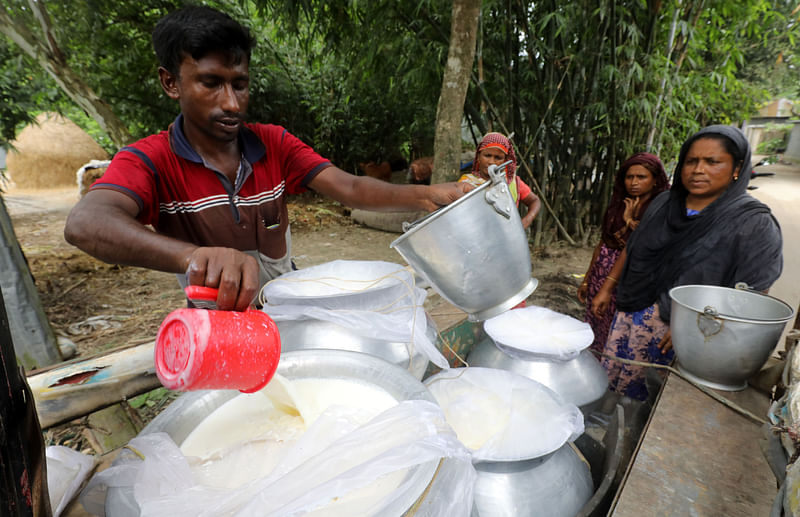 দই তৈরির জন্য গ্রামীণ নারীদের লালন-পালন করা গাভির দুধ কিনে নিচ্ছেন এক গোয়ালা