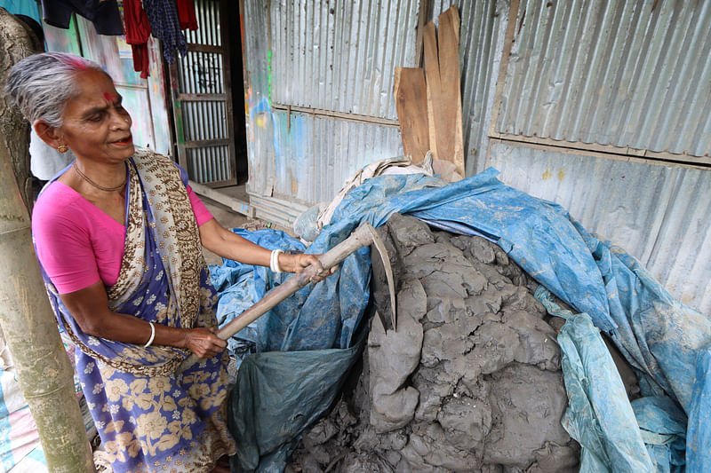 স্তূপ থেকে মাটি কাটছেন এক নারী কারিগর।