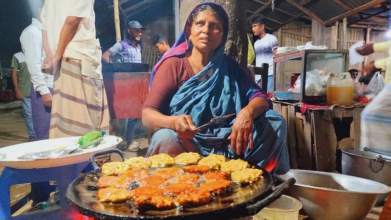দোকানে বসে আলুপরোটা ও পেঁয়াজো ভাজছেন হোসেনে আরা বেগম। সম্প্রতি দিনাজপুরের বিরামপুর রেলস্টেশন এলাকায়ছবি: নূরে আলম সিদ্দিকী