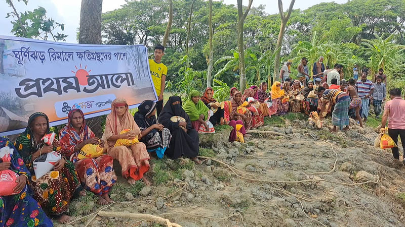 প্রথম আলো ট্রাস্টের উদ্যোগে পটুয়াখালীর দুমকি উপজেলার পাঙ্গাশিয়া ইউনিয়নে ঘূর্ণিঝড় ক্ষতিগ্রস্ত ব্যক্তিদের মধ্যে ত্রাণ বিতরণ করে বন্ধুসভা। আজ সোমবার সকালে উত্তর পাঙ্গাশিয়া গ্রামের পায়রা নদের পাড়ের বেড়িবাঁধ এলাকারছবি: প্রথম আলো