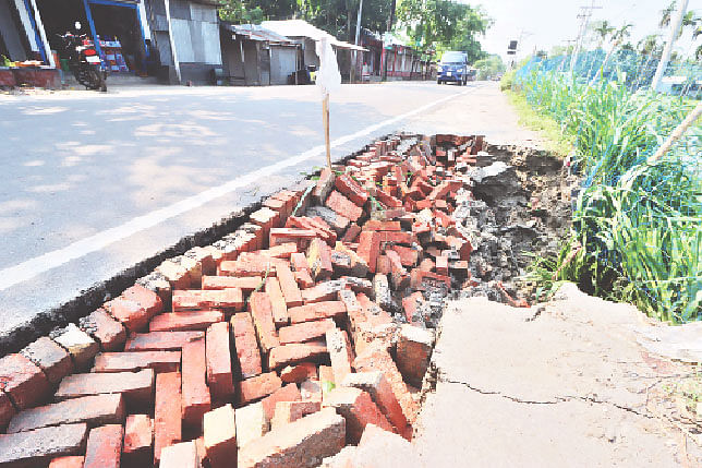 বৃষ্টির পানির তোড়ে মহাসড়কের এক পাশের মাটি ও ইট সরে গেছে। যানবাহন চলছে ঝুঁকি নিয়ে। গতকাল রংপুরের গঙ্গাচড়া উপজেলার মহিপুর এলাকায় আঞ্চলিক মহাসড়কেছবি: মঈনুল ইসলাম