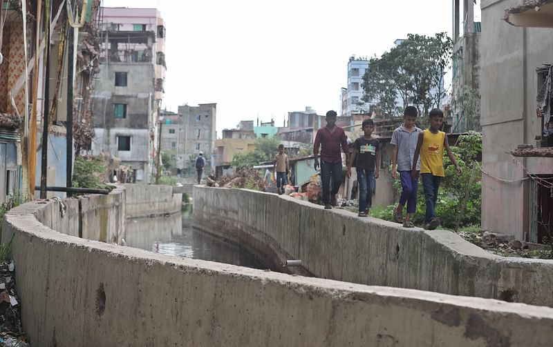 নালার পাড় বরাবর প্রাচীরের ওপর দিয়ে ঝুঁকি নিয়ে চলাচল করছে শিশুসহ অনেকেই।