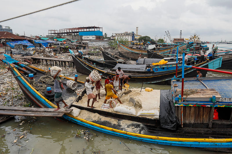 কর্ণফুলী নদীর তীরে নোঙর করে রাখা লবণবাহী ট্রলার থেকে লবণ নামাচ্ছেন শ্রমিকেরা।