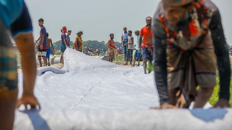 টিউব তৈরি করছেন স্থানীয় লোকজন। এই টিউবে বালু ভরে বাঁধ মেরামত করা হবে।