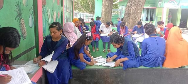 লোডশোডিং ও গরমের কারণে গাছতলায় চলছে পাঠদান। সোমবার দুপুরে বাঘা উপজেলার কাদিরপুর সরকারি প্রাথমিক বিদ্যালয়ে