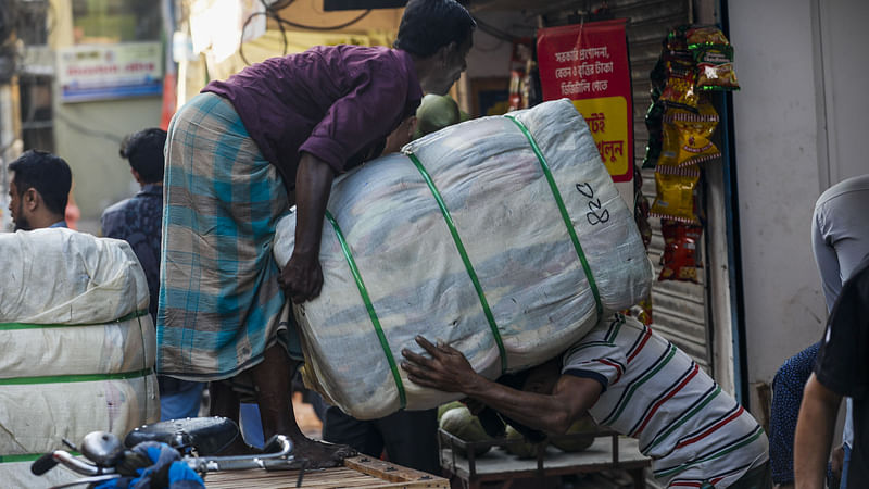 ভ্যান থেকে কাপড়ের গাঁট নামানো হচ্ছে। 