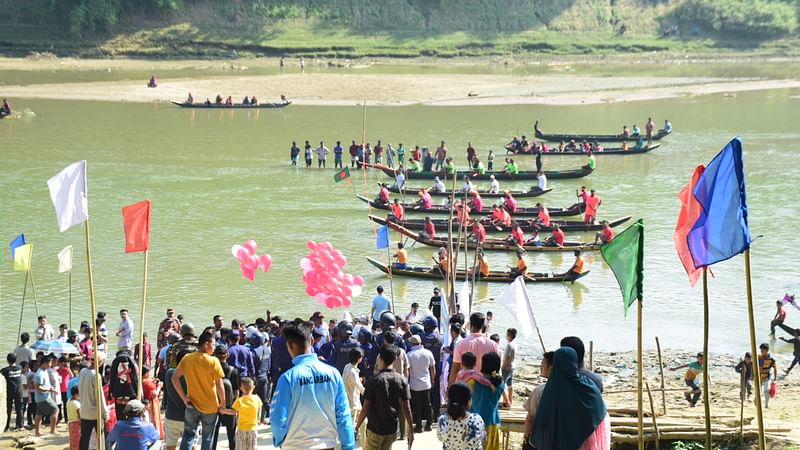 নৌকাবাইচ প্রতিযোগিতা উপভোগ করতে অনেক মানুষ নদের পাড়ে ভিড় করে আছেন।