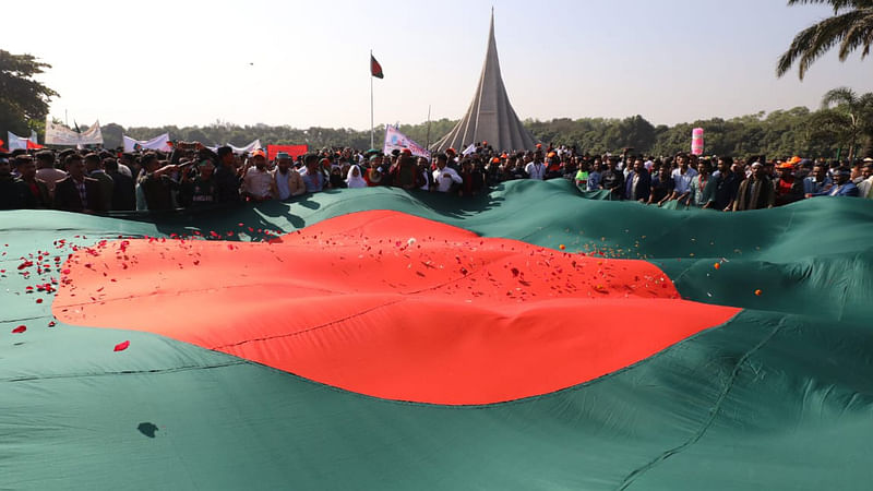 বিশালাকারের জাতীয় পতাকার ওপর ফুলের পাপড়ি ছিটিয়ে দিয়েছেন শ্রদ্ধা জানাতে আসা মানুষেরা