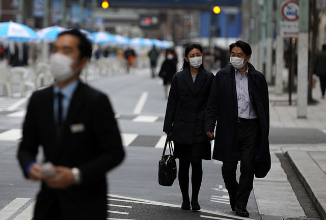 People, wearing protective face masks, following an outbreak of coronavirus, walk on Ginza Boulevard, closed for vehicles during the weekend, in Tokyo, Japan, on 7 March 2020