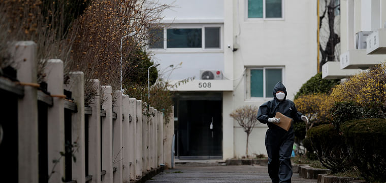 A worker in protective gear makes her way to an apartment building which has entered cohort isolation after a mass coronavirus infection was reported in Daegu, South Korea, on 7 March 2020