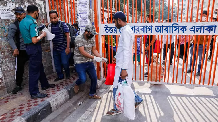People cross a gate defying a lockdown imposed on Tolarbagh in Mirpur area of Dhaka due to coronavirus outbreak on 23 March 2020.
