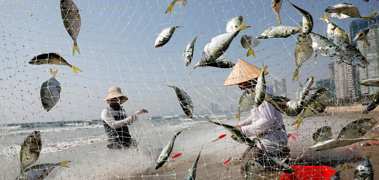 People gather fish on the beach during the coronavirus pandemic