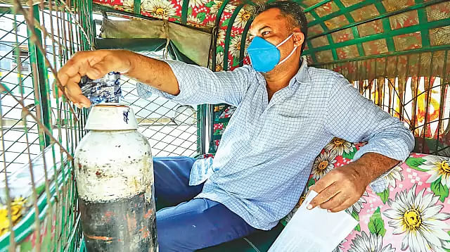 People rush to the Linde Bangladesh plant in Tejgaon to fill oxygen cylinders. This man has collected oxygen for a patient in a hospital at Nikunja in the capital city and is returning by CNG-run auto-rickshaw.