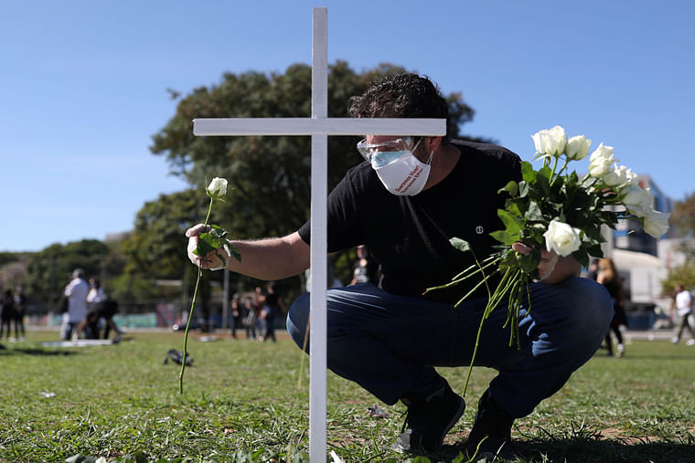 A man places flowers near a cross during a symbolic protest and tribute for health workers who died from the coronavirus disease (COVID-19) in Sao Paulo, Brazil, 20 June 2020.