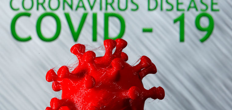 A 3D-printed coronavirus model in front of the words coronavirus disease (COVID-19) on display in this illustration taken on 25 March