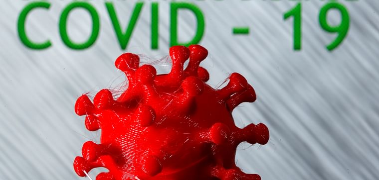 A 3D-printed coronavirus model in front of the words coronavirus disease (COVID-19) on display in this illustration taken on 25 March