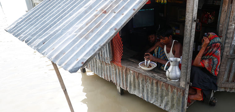 Surrounded by floods, a man has a meal in his small shop in Jamalpur, Bangladesh, 18 July 2020. 