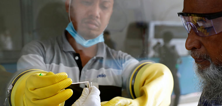 A health worker collects a swab of a man during a coronavirus test in the Mugda Medical College and Hospital as the coronavirus disease (COVID-19) outbreak continues in Dhaka, Bangladesh, 2 July 2020