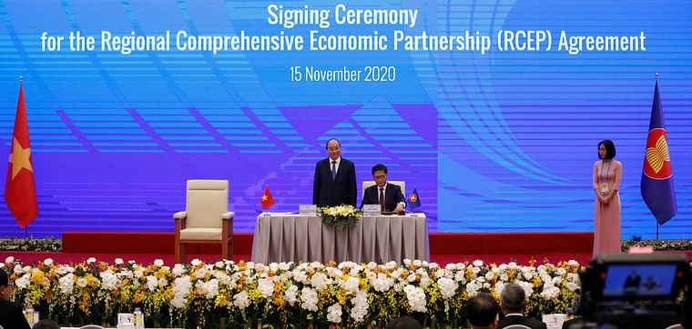 Vietnam's industry and trade minister Tran Tuan Anh (C) signs as Vietnam's prime minister Nguyen Xuan Phuc (L) witnesses during the signing ceremony of the Regional Comprehensive Economic Partnership (RCEP) Agreement during the 37th ASEAN Summit in Hanoi, Vietnam 15 November, 2020