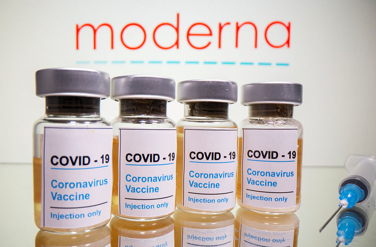 Vials with a sticker reading, "COVID-19 / Coronavirus vaccine / Injection only" and a medical syringe are seen in front of a displayed Moderna logo in this illustration taken 31 October, 2020. 