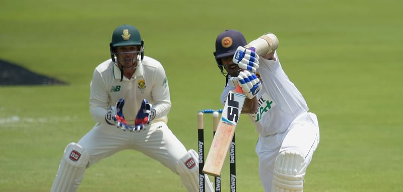 Sri Lanka's Dinesh Chandimal (R) watches the ball after playing a shot as South Africa's captain and wicketkeeper Quinton de Kock (L) looks on during the first day of the first Test cricket match between South Africa and Sri Lanka at SuperSport Park in Centurion on 26 December, 2020.