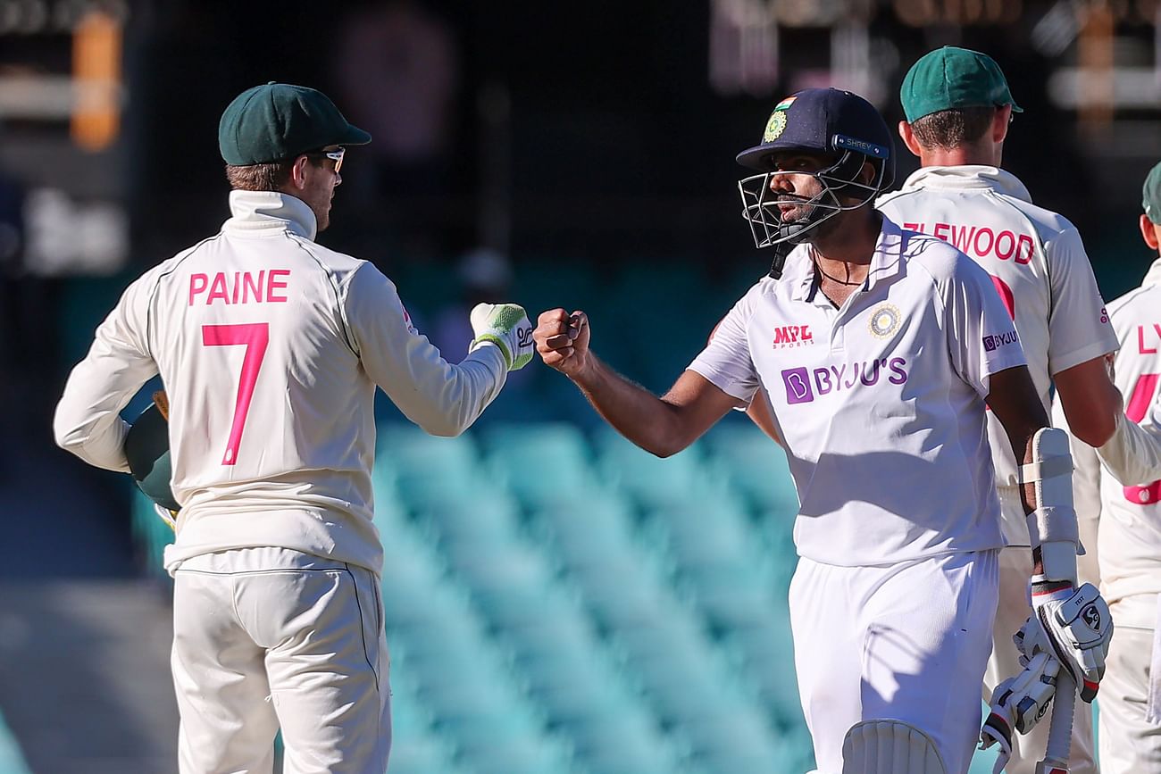 This file photo taken on 11 January, 2021 shows India's Ravichandran Ashwin (R) fist-bumping with Australia's captain Tim Paine (L) at the end of the third cricket Test match between Australia and India at the Sydney Cricket Ground (SCG) in Sydney
