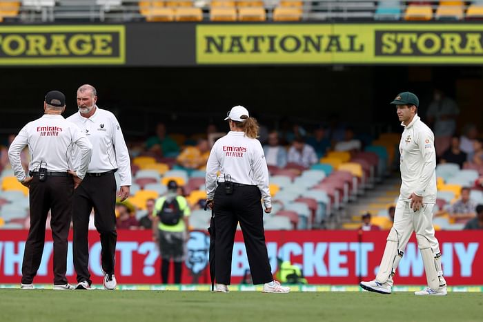  Australia's captain Tim Paine (R) and the umpires examine the pitch area after rain on day two of the fourth cricket Test match between Australia and India at the Gabba in Brisbane on 16 January 2021.