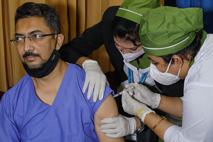A health worker receives a coronavirus vaccine on the first days of vaccination campaign in Mugda Medical College and Hospital in Dhaka on 28 January 2021. 