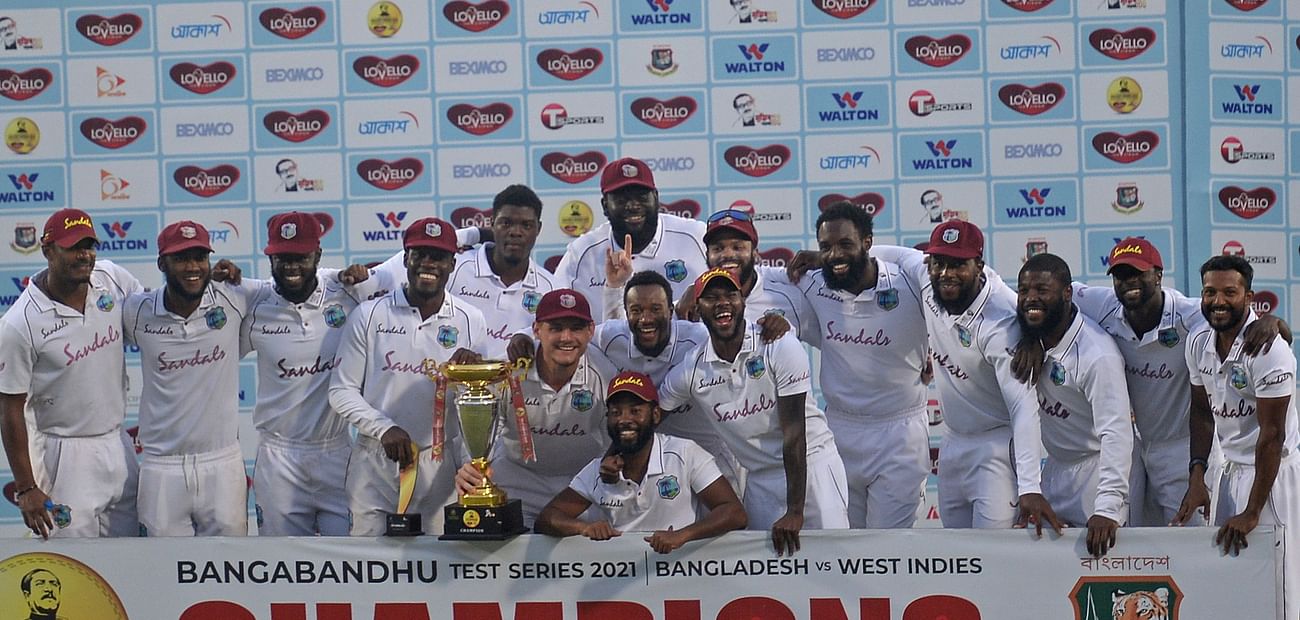 West Indies' players pose with the Test tournament trophy after winning the second Test cricket match against Bangladesh at the Sher-e-Bangla National Cricket Stadium in Dhaka on 14 February , 2021