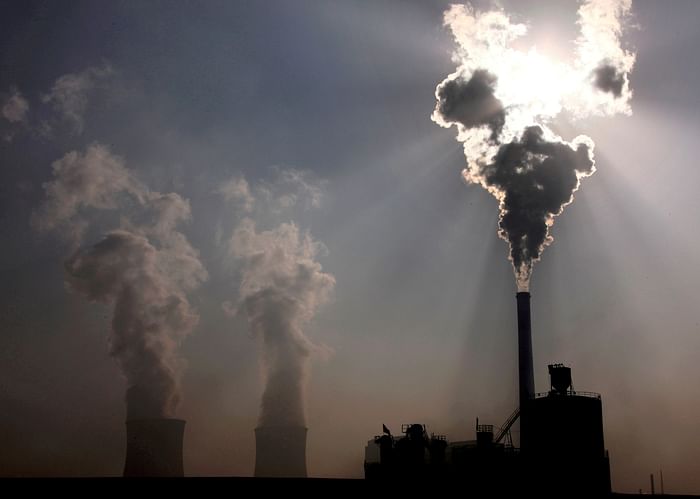 A coal-burning power plant can be seen behind a factory in China's Inner Mongolia Autonomous Region