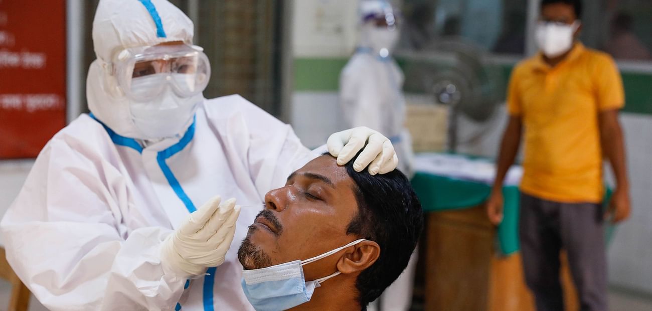 A health worker collects nasal swab of a person for testing coronavirus infection at Mugda Medical College and Hospital, Dhaka
