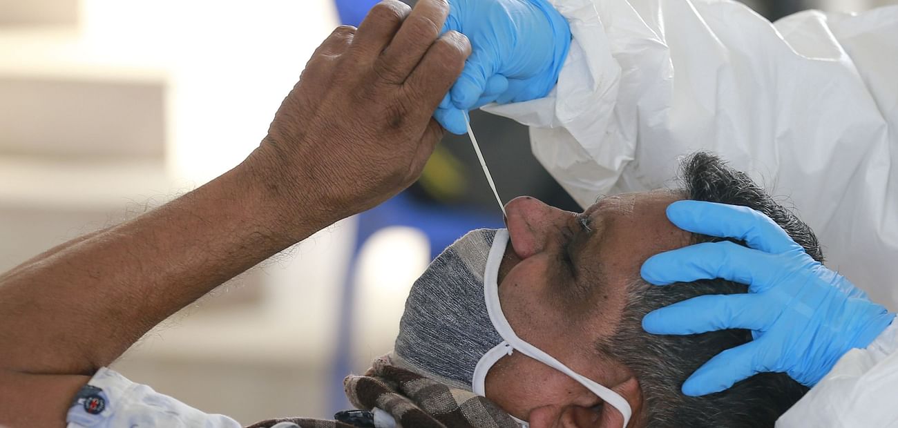 Health worker collects swab of a man for testing Coronavirus infection in Dhaka