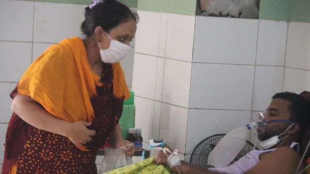 A Covid-19 patient inhales oxygen at Rangpur Medical College Hospital while his wife accompanies him on 5 July 2021.